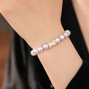 Close-up of elegant purple pearl beaded bracelet with a sparkling zircon bow on a wrist