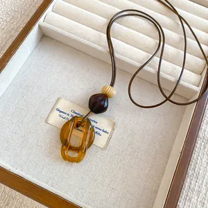 Detailed close-up of interlocked amber resin rings and decorative beads on cord