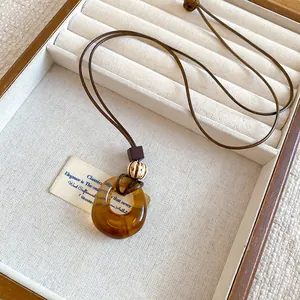 Detailed view of a retro amber resin circular pendant on a brown leather cord necklace