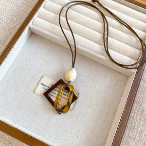 Close-up detail of a vintage resin geometric pendant necklace in a wooden display tray.