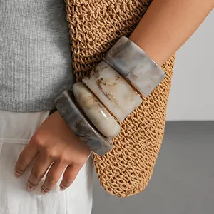 Gros plan de joncs en résine marbrée portés avec un sac en paille tissé neutre élégant