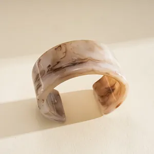 Vue détaillée d'un large bracelet manchette en résine avec un motif marbré marron.