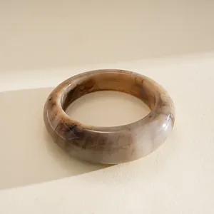 Vue détaillée d'un jonc épais en résine avec des motifs marbrés marron sur fond beige