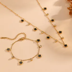 Détail d'un ensemble de bijoux en acier doré avec des étoiles noires et de petites pierres.