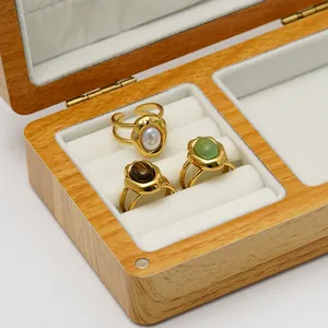Close-up of three stainless steel rings with natural stones in a wooden jewelry box