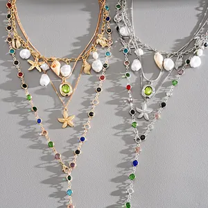 Close-up detail of layered starfish and pearl necklaces in gold and silver finish