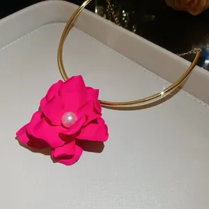 Vista dettagliata di un ciondolo a fiore fucsia su un girocollo rigido dorato chic