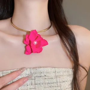 Dettaglio di un girocollo alla moda con un grande fiore rosa acceso e perla