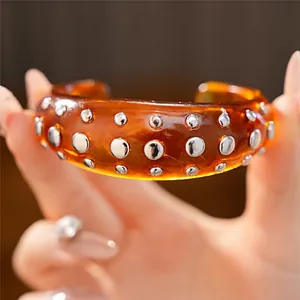 Stoere barnsteenkleurige hars manchetarmband met decoratieve zilveren ronde nagels