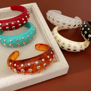 Detailopname van dikke hars armbanden met klinknagels in diverse kleuren