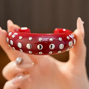 Detailopname van een opvallende rode hars armband met gepolijste zilverkleurige noppen.