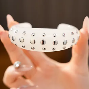 Macro-detail van een witte hars open armband met glanzende zilveren metalen studs.