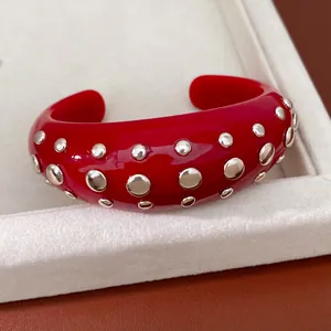 Gedetailleerde macro-opname van een rode kunsthars armband met glanzende zilveren ronde klinknagels