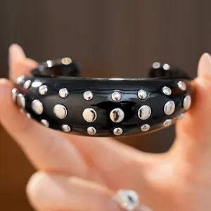 Gedetailleerde weergave van een zwarte hars open armband met zilveren ronde studs decoratie