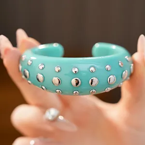Prachtig macrodetail van een turquoise hars manchetarmband met zilveren ronde klinknagels