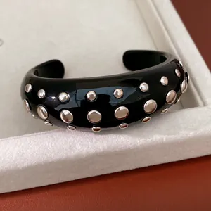 Close-up van zwarte hars manchetarmband met zilveren studs in witte sieraden tray
