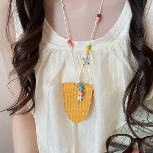 Close-up of a yellow woven leather necklace pendant with colorful beads and starfish charms