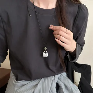 Close-up of minimalist adjustable necklace with a white waterdrop pendant on a model