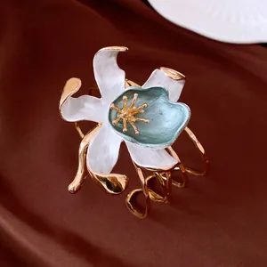 Close-up detail showing the white enamel flower and gold-plated metal of this vintage cuff bracelet