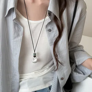 Close-up view of a minimalist silver waterdrop pendant on a long adjustable black cord