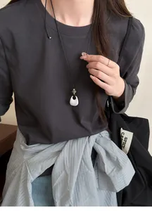 Close-up view of a minimalist teardrop pendant long necklace with adjustable black cord on model