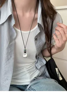 Close-up of minimalist silver teardrop pendant on an adjustable black cord