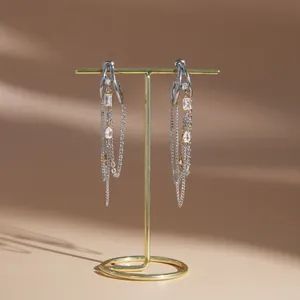 Nahaufnahme von C-förmigen Quastenohrringen aus Edelstahl mit glitzernden Strasssteinen