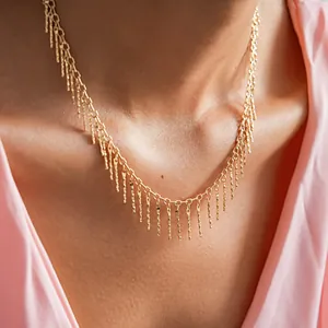 Close-up detail of a gold fringe necklace with copper bars worn on a model's neck.