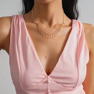 Detailed view of an elegant gold fringe necklace featuring vertical copper bar tassels