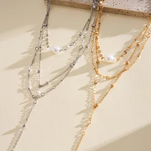 Nahaufnahme von mehrlagigen Perlenhalsketten in Gold und Silber mit eleganten Schatten