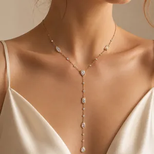 Dettaglio di una collana a Y dorata con zirconi geometrici indossata da una modella