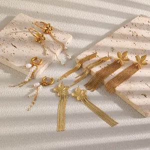 Détail de boucles d'oreilles en acier doré avec motifs floraux et glands de perles