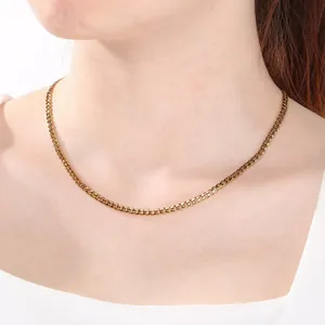 Detalle de un collar de cadena de eslabones NK minimalista dorado en el cuello.