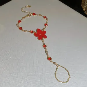 Vista detallada de una pulsera de dedo dorada con flor roja y cristales brillantes