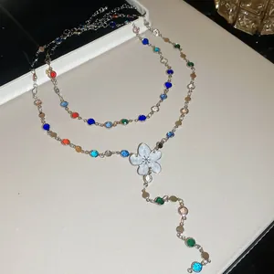 Detalle de los diamantes de imitación de colores y el colgante de flor de esmalte blanco