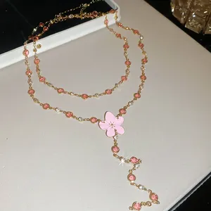 Primer plano de un collar dorado con cristales rosas y un bonito colgante de flor dulce