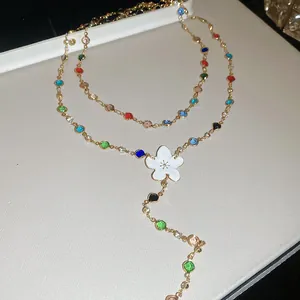 Detalle de un collar en Y colorido con colgante de flor de esmalte blanco pulido