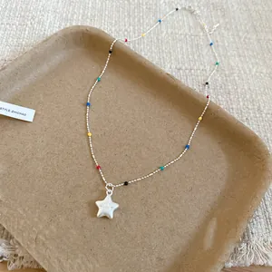 Nahaufnahme einer bunten Perlenkette mit einem weißen Sternanhänger auf einem Tablett