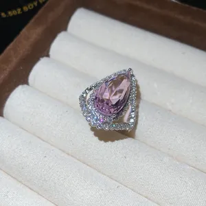 Macro view of a pear-shaped pink gemstone ring with intricate pavé diamond settings.