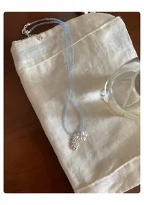 Vue détaillée d'un collier de perles bleu clair avec un pendentif en perles et pierres mauves
