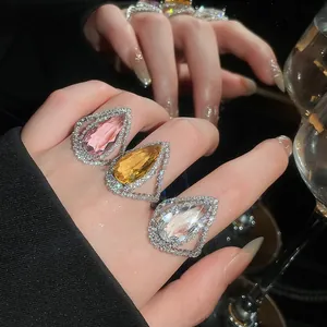 Macro view of luxury teardrop statement rings featuring full pavé diamonds and colorful gems.