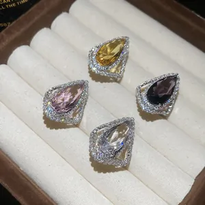 Detailed view of four pear-shaped halo rings with colorful gems in a jewelry tray.