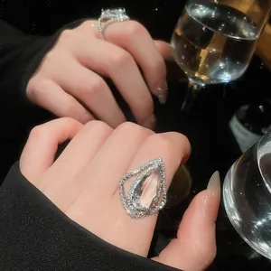 Detail view of luxury water-drop shaped ring with sparkling pavé diamonds on model's hand