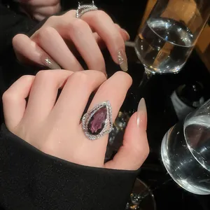 Close-up detail of a luxury teardrop ring with a purple gemstone and sparkling halo.
