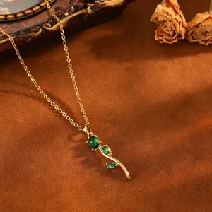 Gros plan du pendentif fleur de tulipe doré avec des pierres précieuses vert émeraude chic