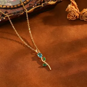 Vue rapprochée d'un collier pendentif tulipe doré orné de pierres bleues et vertes