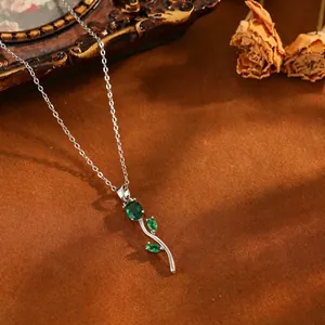 Élégant collier tulipe en argent avec pierres vertes sur un fond rustique.
