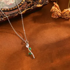 Gros plan d'un collier tulipe avec cristaux verts et blancs sur fond marron texturé.