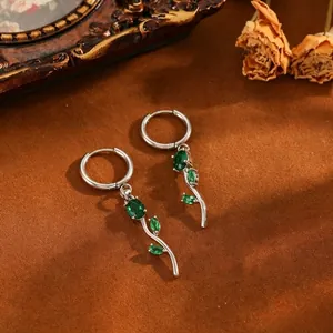 Detailed view of silver tulip earrings with green gemstones and floral leaf design.