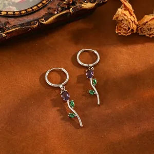 Close-up of stainless steel tulip hoop earrings with purple stone and green leaves